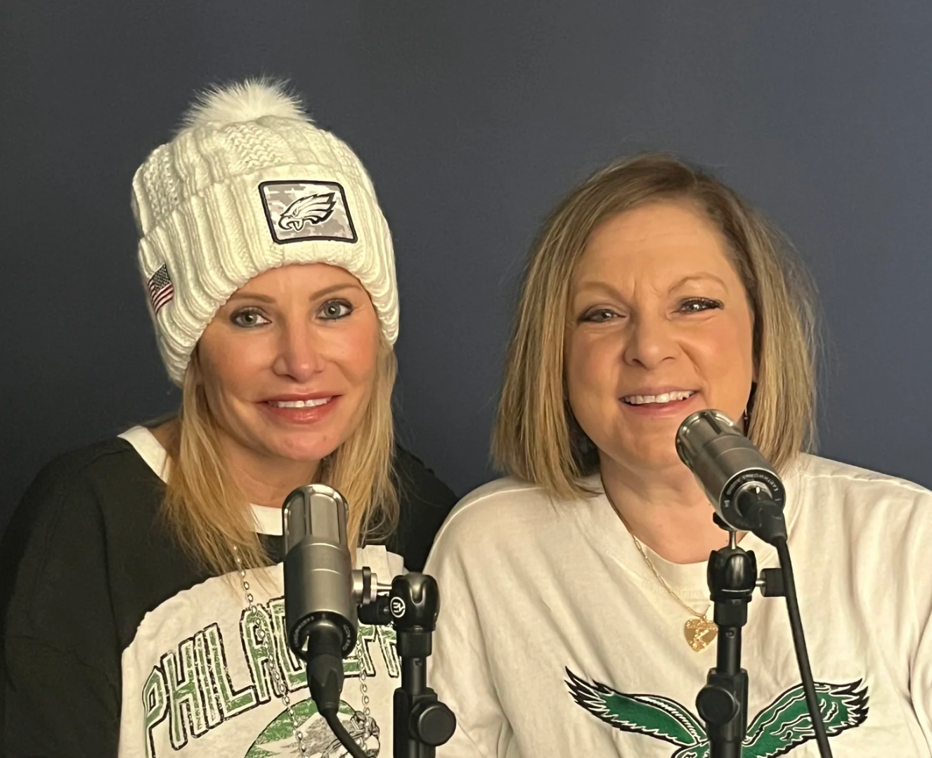 Two women in front of microphones wearing Eagles gear